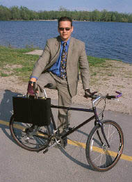 picture of man in suit standing with a bicycle