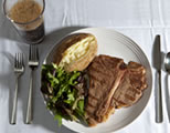 steak, potato, and salad on a plate, plus a soda; click to go to multimedia page at external site; opens in new window